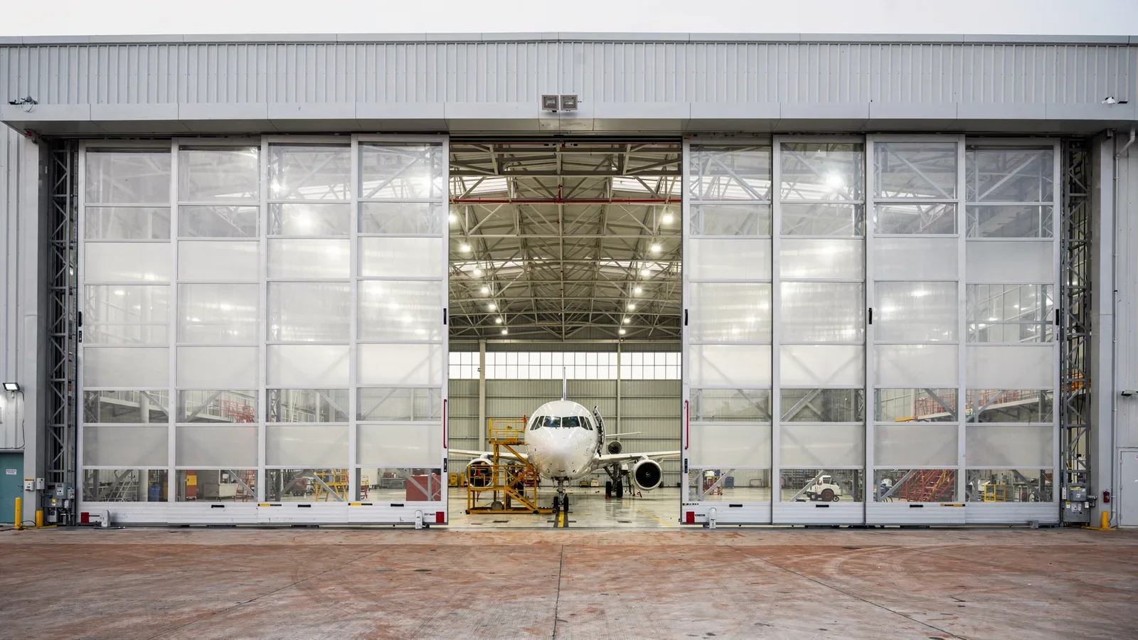 Large multi-leaf sliding hangar doors open at an aircraft maintenance hangar